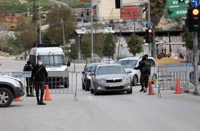 (200323) -- HEBRON, March 23, 2020 -- A Palestinian policeman speaks to a driver at a checkpoint at the entrance of the West Bank city of Hebron, March 23, 2020. Palestinian authorities on Sunday declared a 14-day lockdown on the West Bank as part of measures to combat the spread of coronavirus pandemic. Prime Minister Mohammed Ishtaye announced a ban on transportation and movement between the West Bank districts, urging citizens to stay at home. (Photo by Mamoun Wazwaz Xinhua) MIDEAST-HEBRON-COVID-19-MEASURES XiongxSihao 