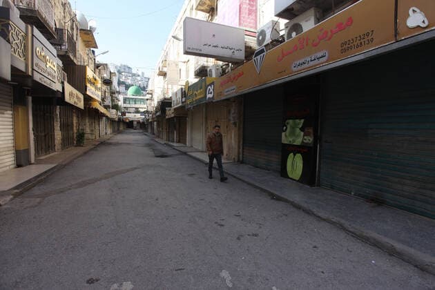 (200323) -- NABLUS, March 23, 2020 -- A Palestinian man walks past closed shops on an empty street in the West Bank City of Nablus, March 23, 2020. Palestinian authorities on Sunday declared a 14-day lockdown on the West Bank as part of measures to combat the spread of coronavirus pandemic. Prime Minister Mohammed Ishtaye announced a ban on transportation and movement between the West Bank districts, urging citizens to stay at home. (Photo by Nidal Eshtayeh Xinhua) MIDEAST-NABLUS-COVID-19-MEASURES XiongxSihao 