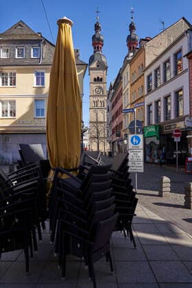 Coronavirus - Koblenz 23.03.2020, Rheinland-Pfalz, Koblenz: Stühle stehen bei Sonnenschein an einem Montag gestapelt in der Altstatt, das Geschäft muss wegen des Coronavirus ruhen. Die Stadt Koblenz ist weitgehend Menschen- und Fahrzeugleer, die die neuen Regeln greifen seit Montag und dienen der Eindämmung der Corona-Pandemie.