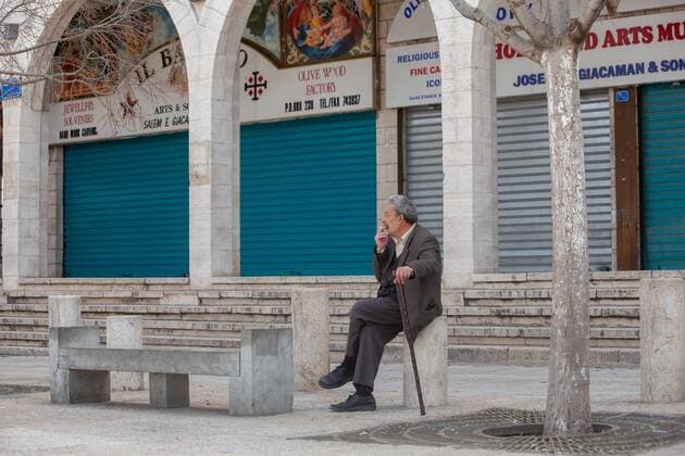 (200323) -- BETHLEHEM, March 23, 2020 -- A Palestinian man sits on an empty street in the West Bank city of Bethlehem, March 23, 2020. Palestinian authorities on Sunday declared a 14-day lockdown on the West Bank as part of measures to combat the spread of coronavirus pandemic. Prime Minister Mohammed Ishtaye announced a ban on transportation and movement between the West Bank districts, urging citizens to stay at home. (Photo by Luay Sababa Xinhua) MIDEAST-BETHLEHEM-COVID-19-MEASURES XiongxSihao 