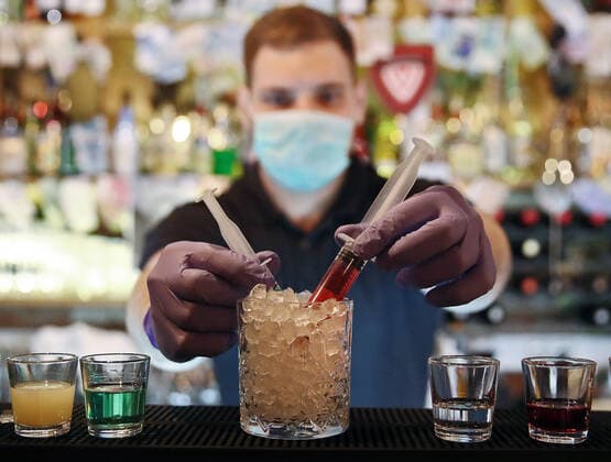 MOSCOW, RUSSIA - MARCH 23, 2020: A bartender in a face mask making a cocktail titled Coronavirus at the Razvedka bar in central Moscow. Sergei Fadeichev TASS  TS0D3286