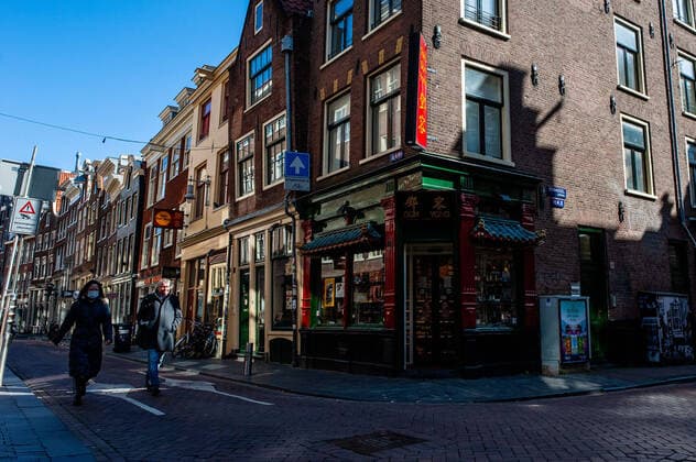 March 23, 2020, Amsterdam, Netherlands: A couple wearing face masks as a precaution against the spread of Coronavirus walk through the streets of Chinatown..Since the Coronavirus hit The Netherlands, most of the cities are empty. A couple of weeks ago, Prime Minister Mark Rutte called to work from home as much as possible and also announced the closure of restaurants, sports clubs, sex clubs, saunas, and cafes. Amsterdam is not formally in lockdown, but the streets and squares are empty. Amsterdam Netherlands - ZUMAs197 20200323_zaa_s197_069 Copyright: xAnaxFernandezx