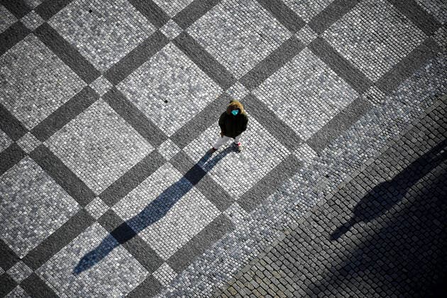 Lonely pedestrian wearing face mask stay in the deserted Old Town Square in Prague, Czech Republic, March 23, 2020. (CTKxPhoto VitxSimanek) CTKPhotoP202003230824201 VIS 004