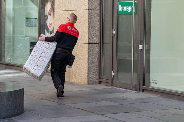 23.03.2020, Berlin, Deutschland, GER - Impressionen aus Berlin während der Ausgangsbeschränkung: Ein Paketbote liefert eine große Packung Toilettenpapier.