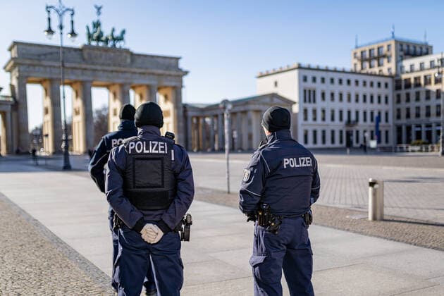 23.03.2020, Berlin, Deutschland, GER - Impressionen aus Berlin während der Ausgangsbeschränkung: Polizisten stehen auf dem sonst menschenleeren Pariser Platz am Brandenburger Tor.
