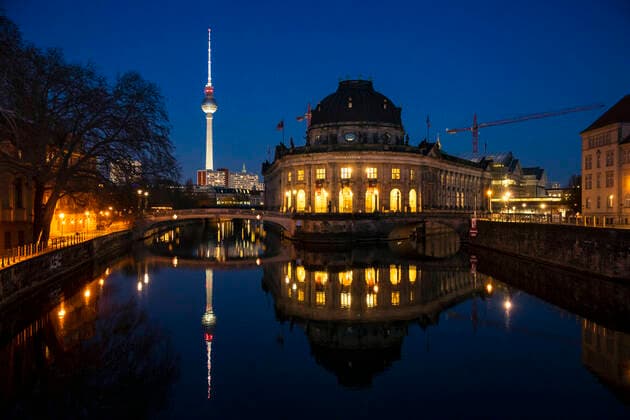 Blick auf dem Bode Museum mit Reflektion auf der Spree waehrend der blauen Stunde in Berlin am 23. Maerz 2020. Um die Verbreitung des Coronavirus (COVID-19) zu verlangsamen beschlossen Bund und Laender weitere Restriktionen. Nachdem Museen, Theatern, Sportveranstaltungen usw verboten wurden sind ab heute Versammlungen mit mehr als zwei Personen in der Oeffentlichkeit grundsaetzlich verboten. Restaurants koennen zum Beispiel nur nich Abholung anbieten. In den Strassen sind ganz wenige Menschen auf den Weg. Oeffentliches Leber weiter in Berlin wegen Coronavirus eingeschraenkt