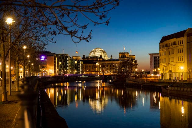 Blick auf dem Reichstag aus dem Reichstagsufer waehrend der blauen Stunde in Berlin am 23. Maerz 2020. Um die Verbreitung des Coronavirus (COVID-19) zu verlangsamen beschlossen Bund und Laender weitere Restriktionen. Nachdem Museen, Theatern, Sportveranstaltungen usw verboten wurden sind ab heute Versammlungen mit mehr als zwei Personen in der Oeffentlichkeit grundsaetzlich verboten. Restaurants koennen zum Beispiel nur nich Abholung anbieten. In den Strassen sind ganz wenige Menschen auf den Weg. Oeffentliches Leber weiter in Berlin wegen Coronavirus eingeschraenkt