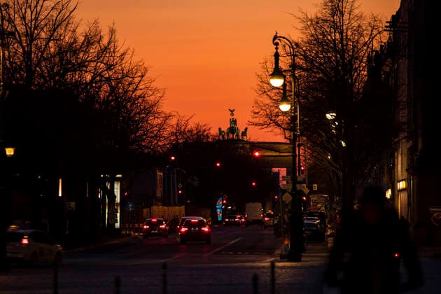 Leeres Unter den Linden mit Blick auf der Quadriga und Brandenburger Tor waehrend der Sonnenuntergang in Berlin am 23. Maerz 2020. Um die Verbreitung des Coronavirus (COVID-19) zu verlangsamen beschlossen Bund und Laender weitere Restriktionen. Nachdem Museen, Theatern, Sportveranstaltungen usw verboten wurden sind ab heute Versammlungen mit mehr als zwei Personen in der Oeffentlichkeit grundsaetzlich verboten. Restaurants koennen zum Beispiel nur nich Abholung anbieten. In den Strassen sind ganz wenige Menschen auf den Weg. Oeffentliches Leber weiter in Berlin wegen Coronavirus eingeschraenkt