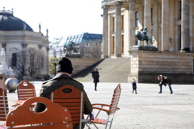 23.03.2020, Berlin - Deutschland. Corona-Krise, Gendarmenmarkt, Mann sonnt sich, Familie spaziert, Tag 1 nach den neuen Regelungen zum Eindämmen des Coronavirus, Menschen sollten nur für die nötigsten Dinge auf die Straße.