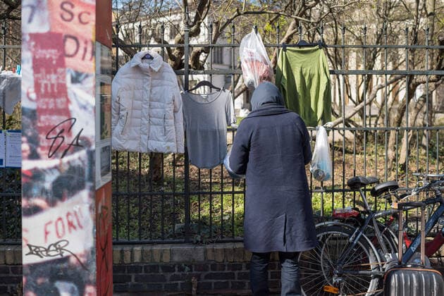 Ein Obdachloser nimmt Lebensmittel vom Spendenzaun an der Evangelische Kirchengemeinde am Weinberg in Berlin-Mitte (Foto vom 24.03.2020). In ganz Deutschland entstehen derzeit sogenannte Spenden- oder Gabenzaeune fuer Obdachlose. Die Menschen werden dazu aufgerufen, in Plastiktueten verpackte Lebensmittel, Hygieneartikel oder Kleiderspenden an die Zaeune zu haengen, damit sich auf der Strasse lebende oder arme Menschen dort versorgen koennen. Wegen der Corona-Pandemie haben viele soziale Einrichtungen wie Tafeln, Nachtcafes und Suppenkuechen aus Infektionsschutzgruenden mittlerweile geschlossen. (Siehe epd-Meldung vom 24.03.2020) Gabenzaeune fuer Obdachlose in ganz Deutschland