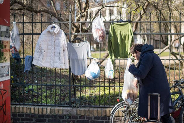 Ein Obdachloser nimmt Lebensmittel vom Spendenzaun an der Evangelische Kirchengemeinde am Weinberg in Berlin-Mitte (Foto vom 24.03.2020). In ganz Deutschland entstehen derzeit sogenannte Spenden- oder Gabenzaeune fuer Obdachlose. Die Menschen werden dazu aufgerufen, in Plastiktueten verpackte Lebensmittel, Hygieneartikel oder Kleiderspenden an die Zaeune zu haengen, damit sich auf der Strasse lebende oder arme Menschen dort versorgen koennen. Wegen der Corona-Pandemie haben viele soziale Einrichtungen wie Tafeln, Nachtcafes und Suppenkuechen aus Infektionsschutzgruenden mittlerweile geschlossen. (Siehe epd-Meldung vom 24.03.2020) Gabenzaeune fuer Obdachlose in ganz Deutschland