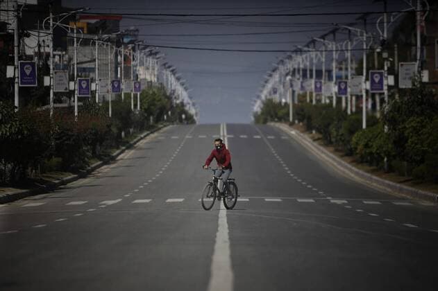(200324) -- KATHMANDU, March 24, 2020 -- A man rides bicycle at an empty road in Kathmandu, Nepal, March 24, 2020. Nepal on Monday decided to enforce a national lockdown for a week effective from Tuesday to prevent the spread of COVID-19. (Photo by Xinhua) NEPAL-KATHMANDU-COVID-19-LOCKDOWN SulavxShrestha 