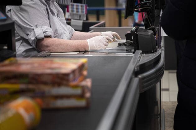 Eine Kassiererin nimmt Geld mit Handschuhen entgegen, aufgenommen in einem Supermarkt in Goerlitz, 24.03.2020. Sachsenweit gibt es Ausgangsbeschraenkungen aufgrund der Ausbreitung des Coronaviruses. Goerlitz Deutschland