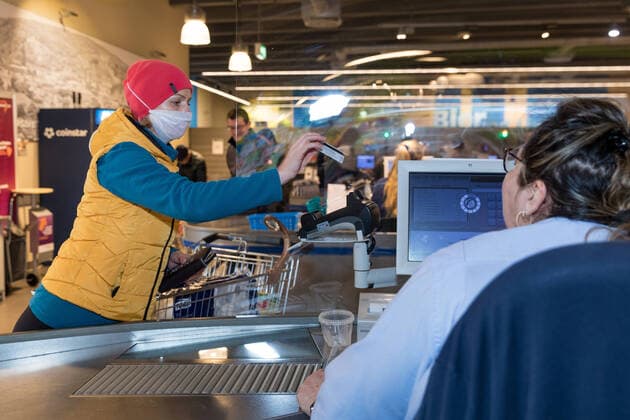 Wuerzburg, City, 21.03.2020, Coronavirus: Einkaufen in Zeiten Coronas Bild: Tag 1 der Ausgangsbeschränkung in Bayern. Zahlreiche Kunden kaufen am Samstag (21.03.20) im EDEKA Frischecenter Trabold im Würzburger Stadtteil Sanderau ein. Hier schützt sich eine Frau mit eine Schutzmaske beim Bezahlen an der Kasse. Copyright: HMBxMediax xPattyxVarasano