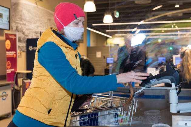 Wuerzburg, City, 21.03.2020, Coronavirus: Einkaufen in Zeiten Coronas Bild: Tag 1 der Ausgangsbeschränkung in Bayern. Zahlreiche Kunden kaufen am Samstag (21.03.20) im EDEKA Frischecenter Trabold im Würzburger Stadtteil Sanderau ein. Hier schützt sich eine Frau mit eine Schutzmaske beim Bezahlen an der Kasse. Copyright: HMBxMediax xPattyxVarasano