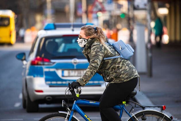 Eine Fahrradfahrererin mit Mundschutzmaske in Berlin am 24. Maerz 2020. Um die Verbreitung des Coronavirus (COVID-19) zu verlangsamen beschlossen Bund und Laender weitere Restriktionen. Nachdem Museen, Theatern, Sportveranstaltungen usw verboten wurden sind ab gestern Versammlungen mit mehr als zwei Personen in der Oeffentlichkeit grundsaetzlich verboten. Restaurants koennen zum Beispiel nur nich Abholung anbieten. Die Menschen scheinen diese Massnahmen zu folgen, da die Stadt menschenleer ist. Oeffentliches Leber weiter in Berlin wegen Coronavirus eingeschraenkt
