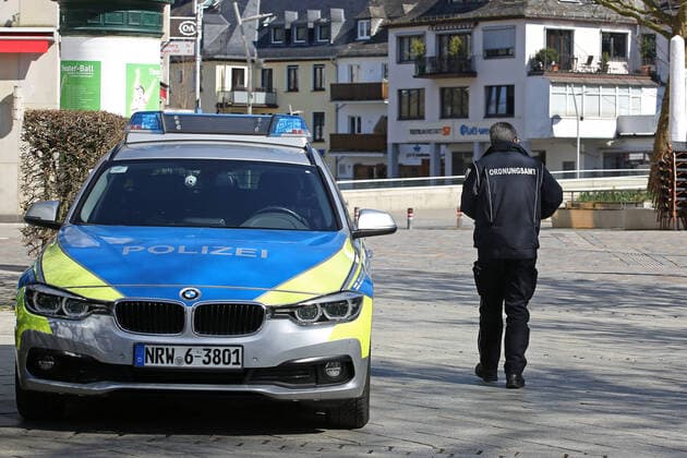 Coronavirus Angst, Auswirkungen wegen des Coronavirus (Covid-19), die Innenstadt von Siegen ist am Mittag fast leer gefegt, Polizeiauto in der Innenstadt, eine Mitarbeiterin vom Ordnungsamt geht vorbei Innenstadt am 25.03.2020 in Siegen Deutschland.