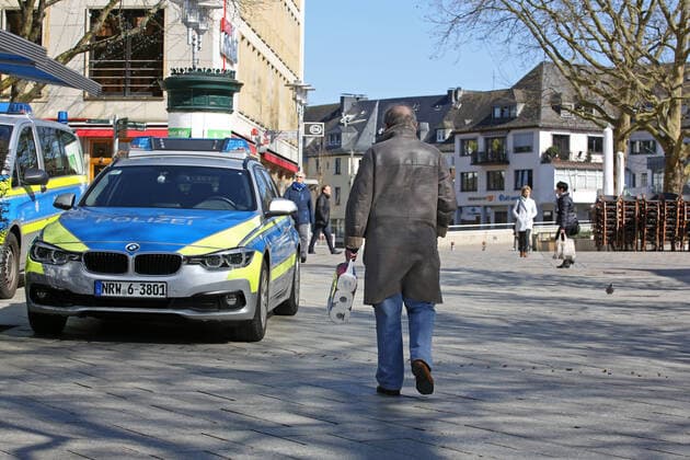 Coronavirus Angst, Auswirkungen wegen des Coronavirus (Covid-19), die Innenstadt von Siegen ist am Mittag fast leer gefegt, Polizeiauto in der Innenstadt, ein Mann geht mit einer Packung Toilettenpapier vorbei Innenstadt am 25.03.2020 in Siegen Deutschland.