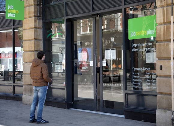 Day Two of Lockdown in Peterborough. A person at the Job Centre Plus only opens the doors a couple of centimetres to speak to a person outside. The country is on lockdown due to the COVID-19 Coronavirus pandemic. People are not allowed to leave home except for minimal food shopping, medical treatment, exercise - once a day, and essential work. COVID-19 Coronavirus lockdown, Peterborough, Cambridgeshire, UK, on March 25, 2020 