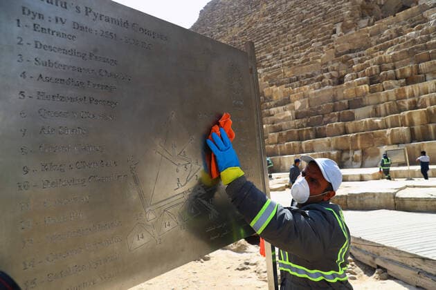 (200325) -- GIZA, March 25, 2020 (Xinhua) -- A staff member cleans a map board near the Pyramids in Giza, Egypt, March 25, 2020. Egypt announced on Tuesday that one COVID-19 case died and 36 new cases were detected, bringing the total number of cases in the country to 402. (Xinhua Ahmed Gomaa) EGYPT-GIZA-PYRAMIDS-DISINFECTION 