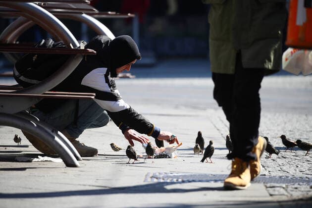 Ein Mann teilt sein Kebab mit Spatz Voegelchen in Berlin am 25. Maerz 2020. Um die Verbreitung des Coronavirus (COVID-19) zu verlangsamen beschlossen Bund und Laender weitere Restriktionen. Nachdem Museen, Theatern, Sportveranstaltungen usw verboten wurden sind ab heute Versammlungen mit mehr als zwei Personen in der Oeffentlichkeit grundsaetzlich verboten. Oeffentliches Leber weiter in Berlin wegen Coronavirus eingeschraenkt