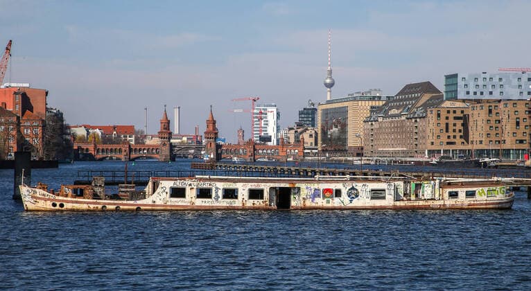 Schiff Dr.Ingrid Wengler Berlin, 25.03.20, Blick ueber die Spree auf Oberbaumbruecke und Skyline mit Fernsehturm. Vorne verlassenes Wrack Schiff Dr.Ingrid Wengler Berlin Berlin Deutschland Spree-Ufer