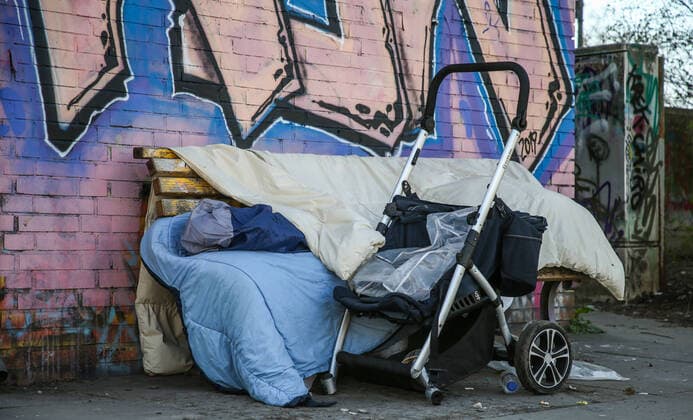 Coronavirus in Berlin Berlin, 25.03.2020, Kreuzberg. Ein Obdachloser schlaeft unter Decken bei knapp 3 Grad Aussentemperatur auf einer Parkbank unter einer Bruecke. Ein Kinderwagen fuer den Transport seiner Habseligkeiten steht neben ihm. Waehrend der Coronakrise haben Obdachlose als Riskiogruppen mit massiven Einschraenkungen ihrer Grundversorgung und medizinischer Hilfe zu kaempfen. Berlin Berlin Deutschland Kreuzberg