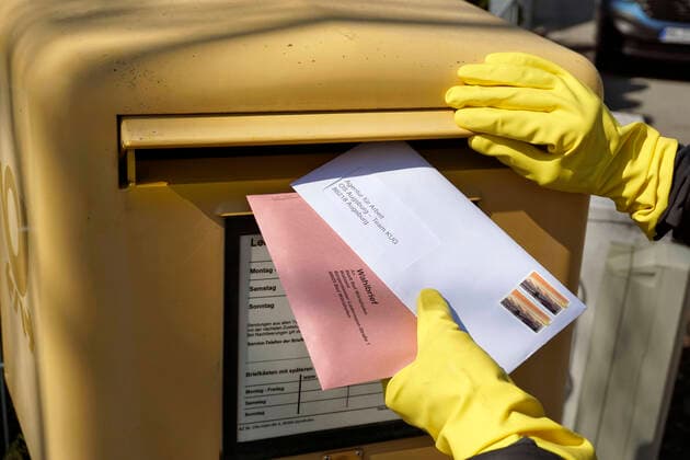 26.03.2020, Gemeinderatswahl, Bürgermeister-Wahl in Bayern 2020, Wahlbezirk Bad Wörishofen in Bayern. Es ist eine Stichwahl nötig, hier wählt eine Bürgerin per Briefwahl und wirft den Umschlag mit Schutzhandschuhen in einen Briefkasten, zusammen mit einem Brief für die Agentur für Arbeit. 26.03.2020, Gemeinderatswahl 2020 26.03.2020, Gemeinderatswahl 2020