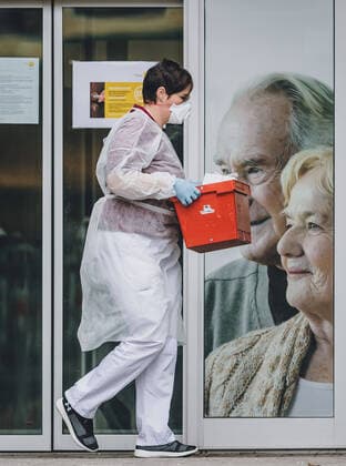 Uttendorf 26.03.2020, Uttendorf, AUT, Coronaviruskrise, Oesterreich, im Bild Mitarbeiterin mit Schutzkleidung holt die abgestellte Post ab. Im Seniorenheim in Uttendorf ist eine Mitarbeiterin erkrankt. Alle Bewohner und Mitarbeiter werden nun auf SARS-CoV-2 getestet. Das Heim wurde unter Quarantaene gestellt Employee with protective clothing. In the retirement home in Uttendorf one of the employees is sick. All residents and employees are now being tested for SARS-CoV-2. The home has been quarantined during the Coronavirus pandemic, Uttendorf, Austria on 2020 03 26.