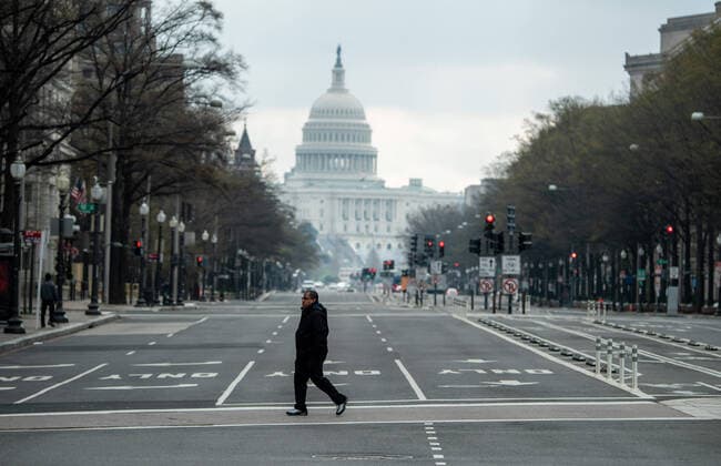 News Bilder des Tages A pedestrian crosses a nearly empty Pensylvania Ave. near the U.S. Capitol Building is seen nearly empty during the morning rush hour after DC Mayor Muriel Bowser closed all nonessential businesses to help stop the spread of the Coronavirus COVID-19, in Washington, D.C on Thursday, March 26, 2020.  WAP20200326305 KEVINxDIETSCH