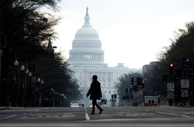 A pedestrian crosses a nearly empty Pensylvania Ave. near the U.S. Capitol Building is seen nearly empty during the morning rush hour after DC Mayor Muriel Bowser closed all nonessential businesses to help stop the spread of the Coronavirus COVID-19, in Washington, D.C on Thursday, March 26, 2020.  WAP20200326326 KEVINxDIETSCH