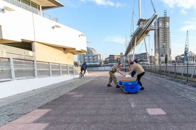 A British Army soldier accompanied by two civilians pulling a cart with medical supplies is seen outside the ExCell Center in London, Thursday, March 26, 2020. The British Government announced Tuesday, that the ExCel Center in east London will become a 4,000 bed temporary hospital to deal with future coronavirus patients, to be called NHS Nightingale. The new coronavirus causes mild or moderate symptoms for most people, but for some, especially older adults and people with existing health problems, it can cause more severe illness or death 