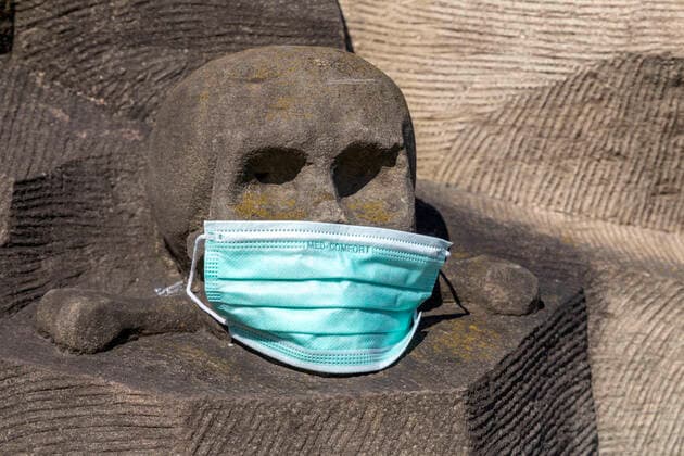 Stuttgart, 27.03.2020: Makabrer Scherz: Ein Totenkopf mit Atemschutzmaske. Kreuzigungsgruppe von Hans Seyfer an der Leonhardskirche Stuttgart. DEU, Deutschland, Baden-Württemberg