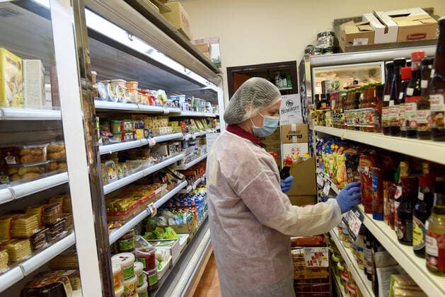 An Israeli workers wears protective mask and gloves while stocking shelves in a market in Jerusalem, on Friday, March 27, 2020. Eleven Israelis have died from the coronavirus, while more than 3,000 have been diagnosed with the disease. The Israeli government has imposed tight restrictions of movement, leaving only essential stores open in an effort to stop the spread of the coronavirus.  JER2020032701 DEBBIExHILL