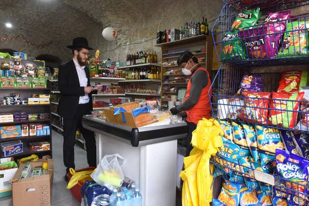 A worker wears protective mask and gloves in a shop in Jerusalem, on Friday, March 27, 2020. Eleven Israelis have died from the coronavirus, while more than 3,000 have been diagnosed with the disease. The Israeli government has imposed tight restrictions of movement, leaving only essential stores open in an effort to stop the spread of the coronavirus.  JER2020032716 DEBBIExHILL