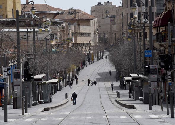 Israelis walk on an empty street in Jerusalem, on Friday, March 27, 2020. Eleven Israelis have died from the coronavirus, while more than 3,000 have been diagnosed with the disease. The Israeli government has imposed tight restrictions of movement, leaving only essential stores open in an effort to stop the spread of the coronavirus.  JER2020032718 DEBBIExHILL