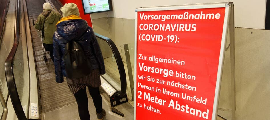 Corona-Krise - Virus - Viren - Corona-Pandemie - Corona-Einschränkungen - Angst vor dem Coronavirus - Schutz vor dem Coronavirus - Covid 19 - Corona-Warnung - 27.03.2020, Berlin, Deutschland, GER - Warnhinweis Corona - Vorsorgemaßnahme CORONAVIRUS (COVID-19): Zur allgemeinen Vorsorge bitten wir Sie zur nächsten Person in Ihrem Umfeld 2 Meter Abstand zu halten. Kunden auf einer Rolltreppe.