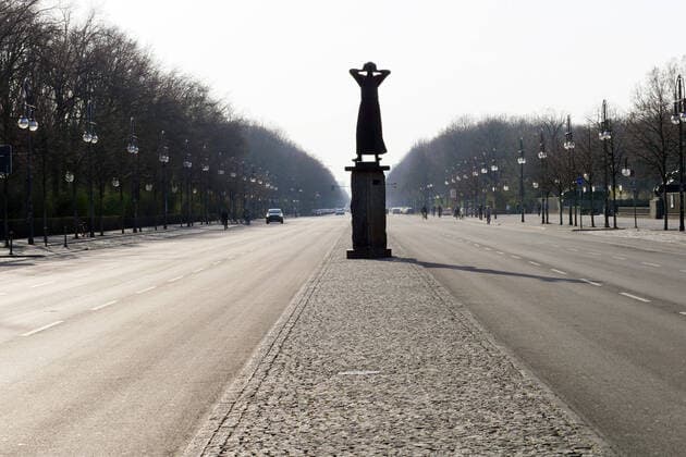 27.03.2020, Berlin - Deutschland: Corona-Krise; geisterhafte Leere auf der Straße des 17. Juni, nahezu kein Verkehr, keine Autos, aber die Silhouette des Mahnmals Der Rufer .