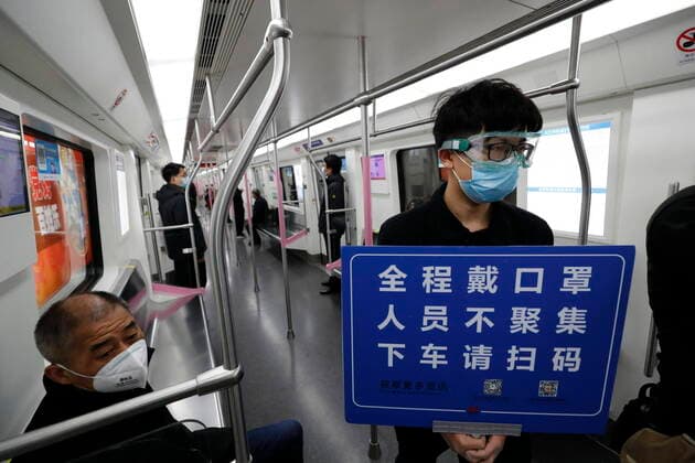 (200328) -- WUHAN, March 28, 2020 -- A train safety crew member holds a placard to remind passengers of scanning the QR code for real-name registration and wear masks on a train along the Wuhan Metro Line 2 in Wuhan, central China s Hubei Province, March 28, 2020. Six metro lines in Wuhan resumed operation starting from Saturday, a new sign that life is gradually returning to normal in the hardest-hit city. Passengers are required to scan the QR code for real-name registration and take temperature checks before taking the subway. Each train is equipped with a train safety crew member to help guide and serve the passengers. ) CHINA-HUBEI-WUHAN-METRO-OPERATION RESTORATION (CN) ShenxBohan 