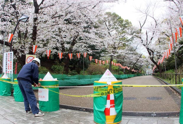 March 28, 2020, Tokyo, Japan - A worker fixes a rope and keep out sign as a cherry blossom viewing road is closed at Tokyo s Ueno park on Saturday, March 28, 2020. Tokyo governor Yuriko Koike requested people to stay at home over the weekend for outbreak of new coronavirus.  (124828084)