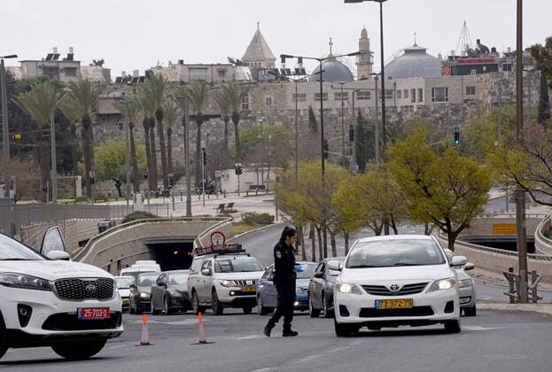 An Israeli police stops cars, as part of coronavirus restrictions, outside the Old City of Jerusalem, on Saturday, March 28, 2020. The Israeli government has imposed tight restrictions of movement, leaving only essential stores open in an effort to stop the spread of the coronavirus disease.  JER2020032801 DEBBIExHILL