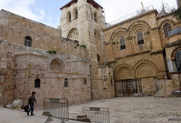 A Palestinian boy walk past the Church of the Holy Sepulchre, closed because of the coronavirus, in Jerusalem s Old City, on Saturday, March 28, 2020. The Israeli government has imposed tight restrictions of movement, leaving only essential stores open in an effort to stop the spread of the coronavirus disease.  JER2020032810 DEBBIExHILL