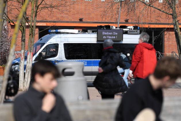 Berliner Polizisten machen Lautsprecherdurchsagen und fordert alle auf, die auf der Wiese sitzen oder liegen, sich zu entfernen. Sport treiben bzw. sich bewegen ist erlaubt. Auf Displays an dem Polizeifahrzeug steht, Bleiben Sie zu Hause! Corona-Streife am Gleisdreieck