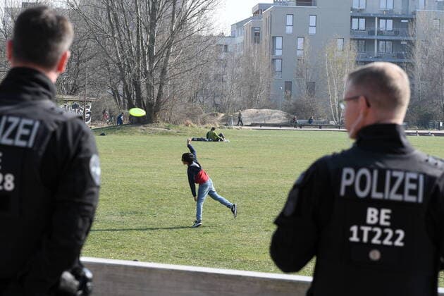 Berliner Polizisten machen Lautsprecherdurchsagen und fordert alle auf, die auf der Wiese sitzen oder liegen, sich zu entfernen. Sport treiben bzw. sich bewegen ist erlaubt. Corona-Streife am Gleisdreieck