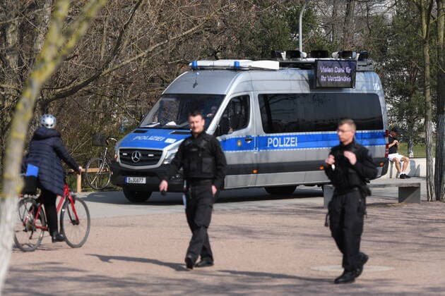 Berliner Polizisten weisen auf die Ausgangs- und Kontaktsperren hin. Zudem machen sie Lautsprecherdurchsagen und fordern alle auf, die auf der Wiese im Park am Gleisdreieck sitzen oder liegen, sich zu entfernen. Sport treiben bzw. sich bewegen ist erlaubt. Corona-Streife am Gleisdreieck