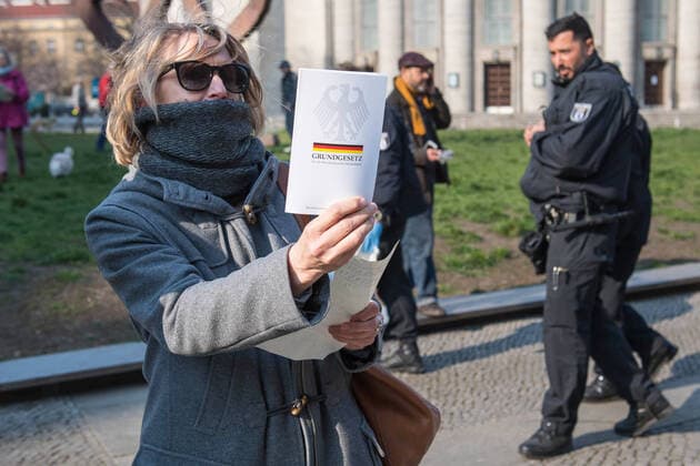 Trotz Ausgangsbeschraenkungen haben am Samstag (28.03.2020) auf dem Rosa-Luxemburg-Platz vor der Berliner Volksbuehne etwa 80 Menschen an einer Hygienedemo fuer Verfassung, Grundrechte & transparente Gestaltung der neuen Wirtschaftsregeln durch die Menschen selbst teilgenommen. Jeweils mit dem Grundgesetz unter dem Arm forderten die Demonstranten im Kreis laufend unter anderem die Beendigung des Notstands-Regimes , demokratische Regeln fuer unser kuenftiges Wirtschaftssystem und die Verhinderung obrigkeitsstaatlicher Schikanen . (Siehe epd-Meldung vom 28.03.2020)