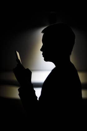 Symbolfoto zum Thema Einsamkeit und Isolation: Eine Frau sitzt nachts auf der Couch und schaut in ein Smartphone. Berlin, 25.03.2020. Um die Ausbreitung des Coronavirus, COVID-19, SARS-CoV-2, zu verlangsamen, wurden in Deutschland Ausgangssperren angeordnet. Alleinstehenden Menschen droht durch Isolation und Quarantaene Einsamkeit und Depressionen. Soziale Kontakte kâˆöâˆ‚nnen nur digital aufrecht erhalten werden. Berlin Deutschland