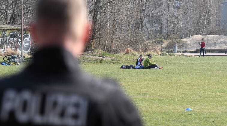 Berliner Polizisten weisen auf die Ausgangs- und Kontaktsperren hin. Zudem machen sie Lautsprecherdurchsagen und fordern alle auf, die auf der Wiese im Park am Gleisdreieck sitzen oder liegen, sich zu entfernen. Sport treiben bzw. sich bewegen ist erlaubt. Corona-Streife am Gleisdreieck