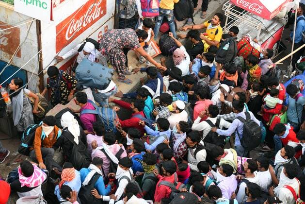 NEW DELHI, INDIA - MARCH 28: Migrant workers try to jump a wall at Anand Vihar Bus Terminus near the Delhi - UP border following Uttar Pradesh government?s call to arrange buses for the workers returning to their native state, on Day 4 of the 21 day nationwide lockdown -- to check the spread of coronavirus, on March 28, 2020 in New Delhi, India. (Photo by Raj K Raj Hindustan Times ) Coronavirus Update: Amid Lockdown, A Sea Of Migrants In Delhi-NCR Try To Find Their Way Back Home