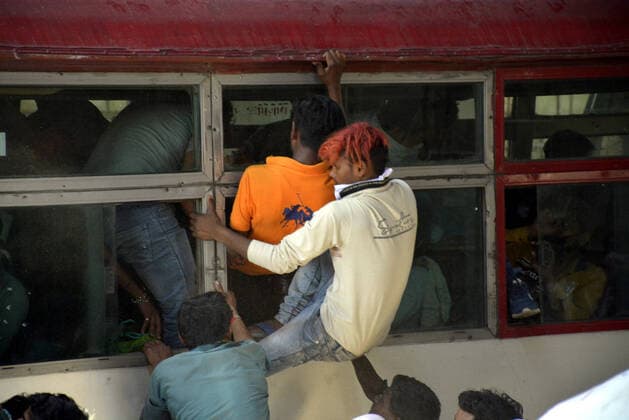 GHAZIABAD, INDIA - MARCH 28: Migrant workers try to board an overcrowded bus bound to their native state on Day 4 of the 21 day nationwide lockdown -- to check the spread of coronavirus, at Lal Kuan bus stand, on March 28, 2020 in Ghaziabad, India. (Photo by Sakib Ali Hindustan Times ) Coronavirus Update: Amid Lockdown, A Sea Of Migrants In Delhi-NCR Try To Find Their Way Back Home
